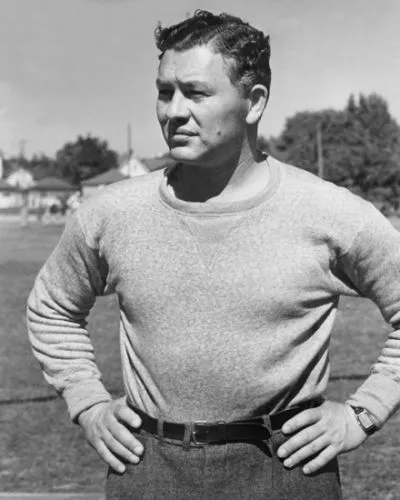 Curly Lambeau in a sweater with his hands on his hips