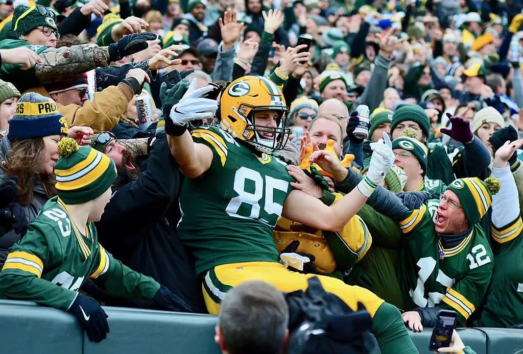 A Packers player leaping into the stands at Lambeau Field